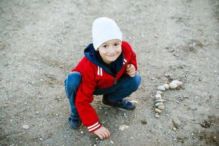 Little boy playing on road with gravels, outdoorの写真素材