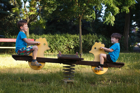 Happy little boys on seesaw in parkの写真素材