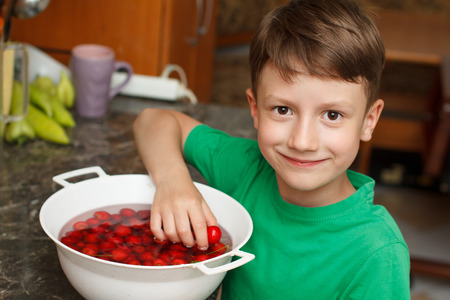 Cute little boy eating cherry in kitchenの写真素材