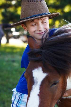 Little boy and cute pony, outdoor portraitの写真素材