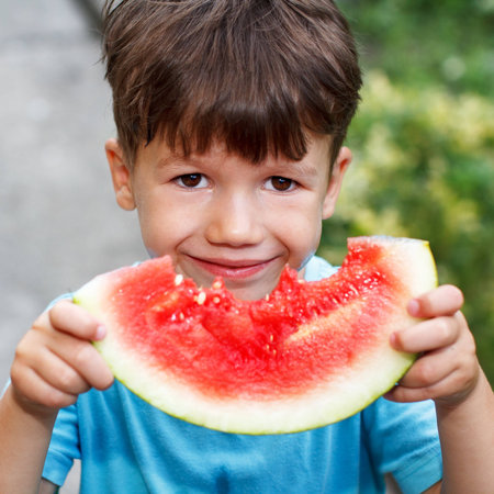 Little cute caucasian boy holding melon, outdoor portraitの写真素材