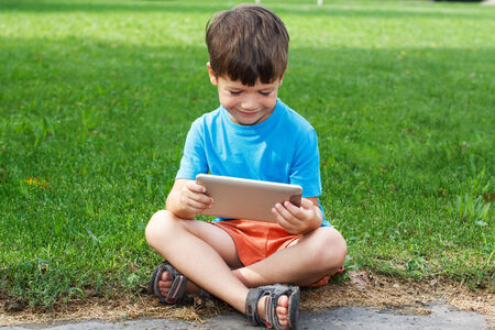 Little caucasian boy smile with tablet outdoorの写真素材