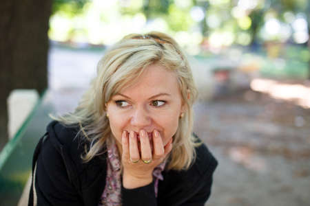 Middle aged blonde woman in park looking away, autumn portrait