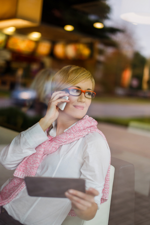 Happy young manager call by smartphone in restaurant, behind glassの写真素材