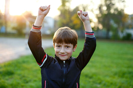 Little boy hands up winning, outdoor portraitの写真素材