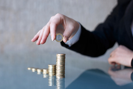 Businesswoman building growing one euro columns, saving money concept, closeup