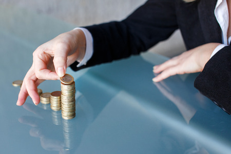 Businesswoman building growing one euro columns, saving money conceptの写真素材