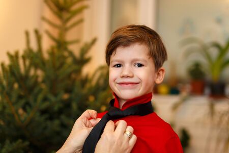Mother help dress little boy at Christmas, indoor portraitの写真素材