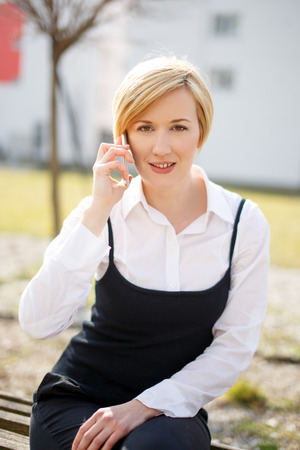 Blonde businesswoman calling outdoor in parkの写真素材