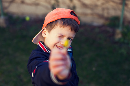 Little boy in cap showing yellow flower, motherの写真素材