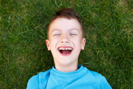 Little caucasian boy laughing in grass, outdoor portrait