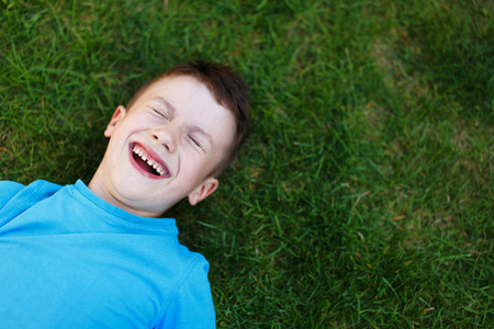Little boy laughing in grass, outdoor portraitの写真素材