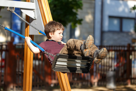 Little preschooler boy swinging in park outdoorの写真素材