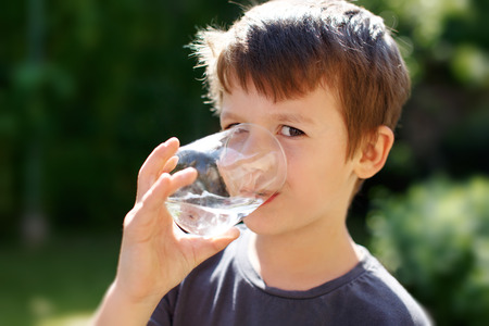 Little caucasian boy drink water in natureの写真素材