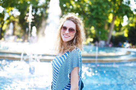 Young readhead woman with curly hair at park in sunsetの写真素材