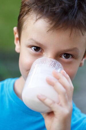 Little boy drink fresh milk in nature, outdoor portraitの写真素材