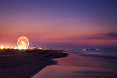 Colorful sunset with ferris wheel on beachの写真素材