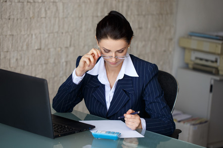 Entrepreneur calculating expenses in office on blank white paperの写真素材