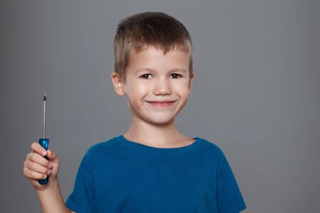 Little boy holding screwdriver on grey backgroundの写真素材