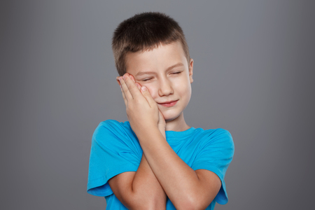 Little boy with toothache on grey backgroundの写真素材