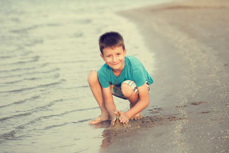 Little boy building sand fortress on beach in vintage style, summer holidayの写真素材