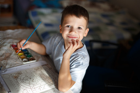 Happy little preschooler boy painting coloring book at homeの写真素材