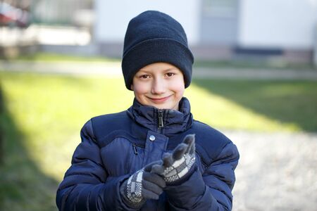 Little boy putting on mitten, outdoor portrait at winterの写真素材