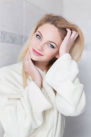 Blonde woman in bathrobe at bathroom, freshness at morningの写真素材