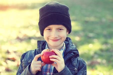 Little hipster schoolboy holding fresh red appleの写真素材