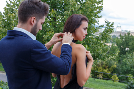 Elegant stylish man help dressing woman outdoor