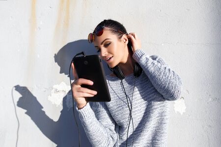 Young stylish hipster woman with tablet and headphones outdoor