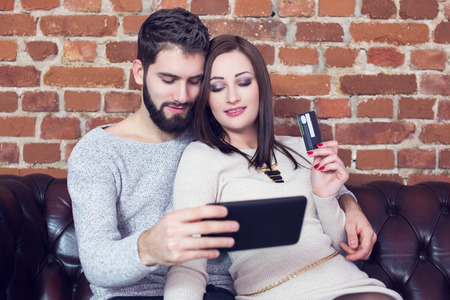 Couple online shopping by tablet and credit card indoorの写真素材