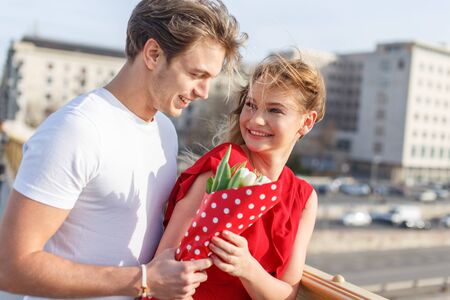Young caucasian man giving bouquet to woman, happy coupleの写真素材