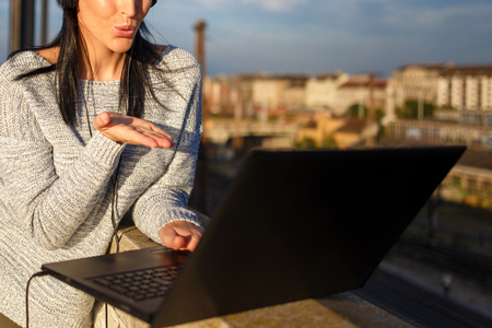 Young woman sending kisses by laptop outdoor closeup, wireless technologyの写真素材