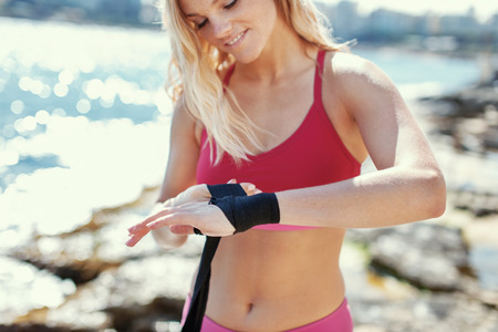 Blonde woman kickboxer wraps hand outdoorの写真素材