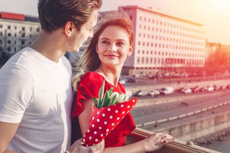 Young couple on first date in sunset, man surprise with bouquetの写真素材