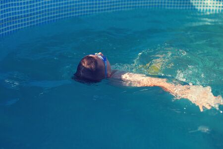 Little kid lying back on water in swimming pool, relaxingの写真素材