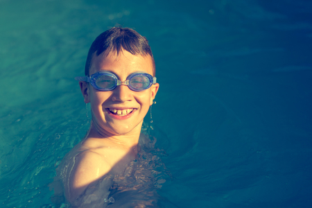 Happy little boy laughing in swimming poolの写真素材
