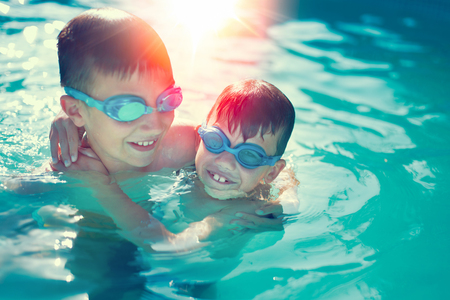 Happy little kids have fun in swimming pool graded in sunsetの写真素材
