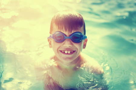 Happy little boy enjoying summer holiday in swimming pool vintage style