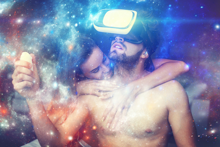Naked couple playing virtual reality at home, man with VR glasses opening magical universe of fantasyの写真素材