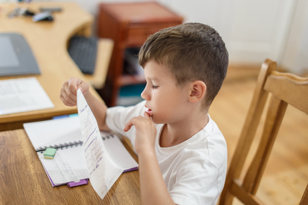 Little schoolboy checking his homework mistakes, thinkingの写真素材