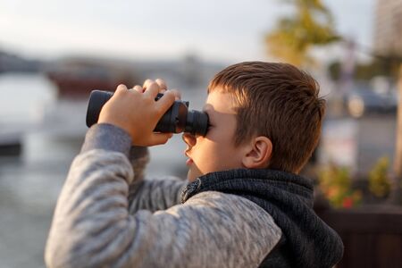 Little caucasian boy watching, looking, gazing, searching for by binocularsの写真素材