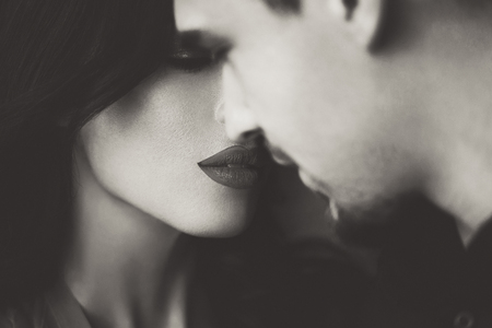 Woman with red lips closing eyes before kissing young man, black and white artistic sepiaの写真素材