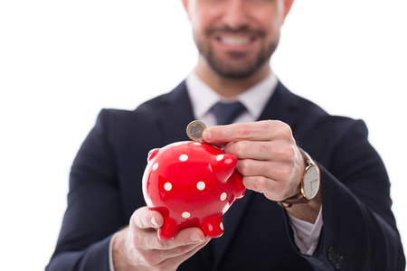 Man in formal wear put one euro coin into piggy bank isolatedの写真素材
