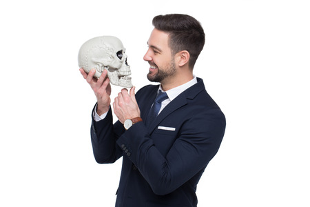 Businessman holding skull and smile portrait, business competition concept, isolated on whiteの写真素材