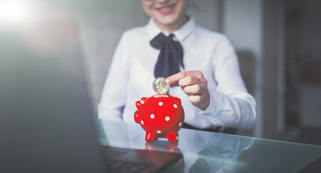 Young businesswoman drop bitcoin into red dotted piggy bank, cinematic styleの写真素材