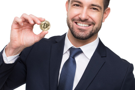Young businessman in formal wear holding bitcoin with toothy smile, isolated on whiteの写真素材