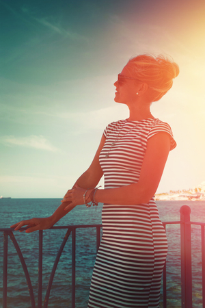 Young blonde woman at mediterranean sea looking away, vintage styleの写真素材