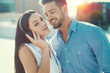 Young trendy caucasian couple in sunset woman with headphonesの写真素材
